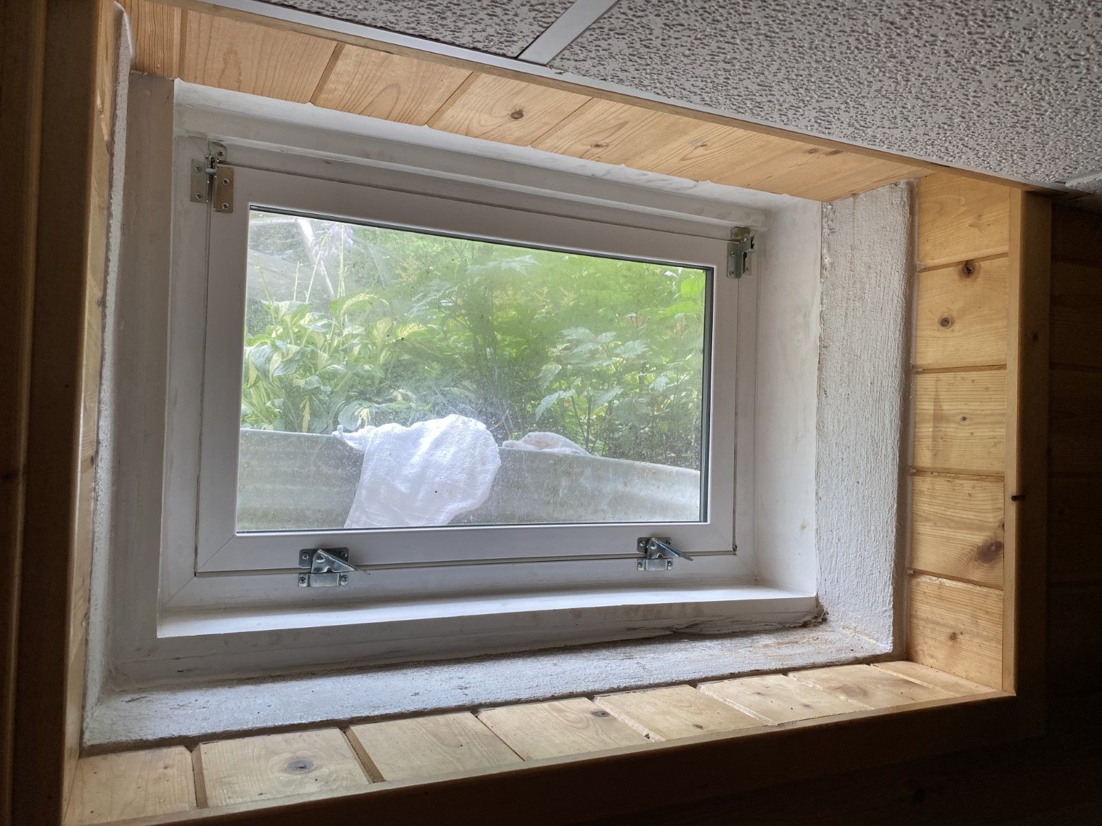 A window in a room with a wooden frame and a ceiling.