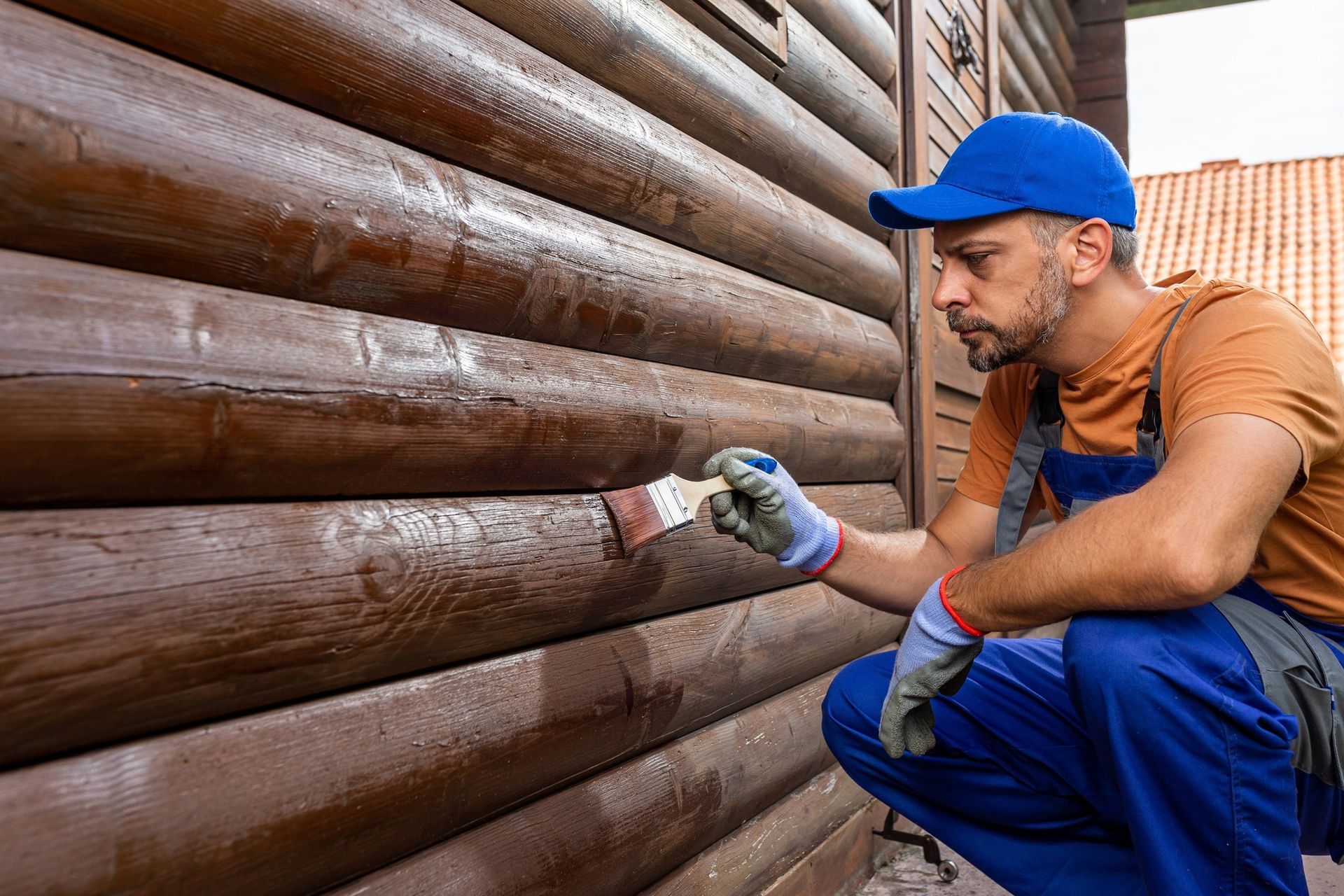 A man is painting a wooden wall with a brush.