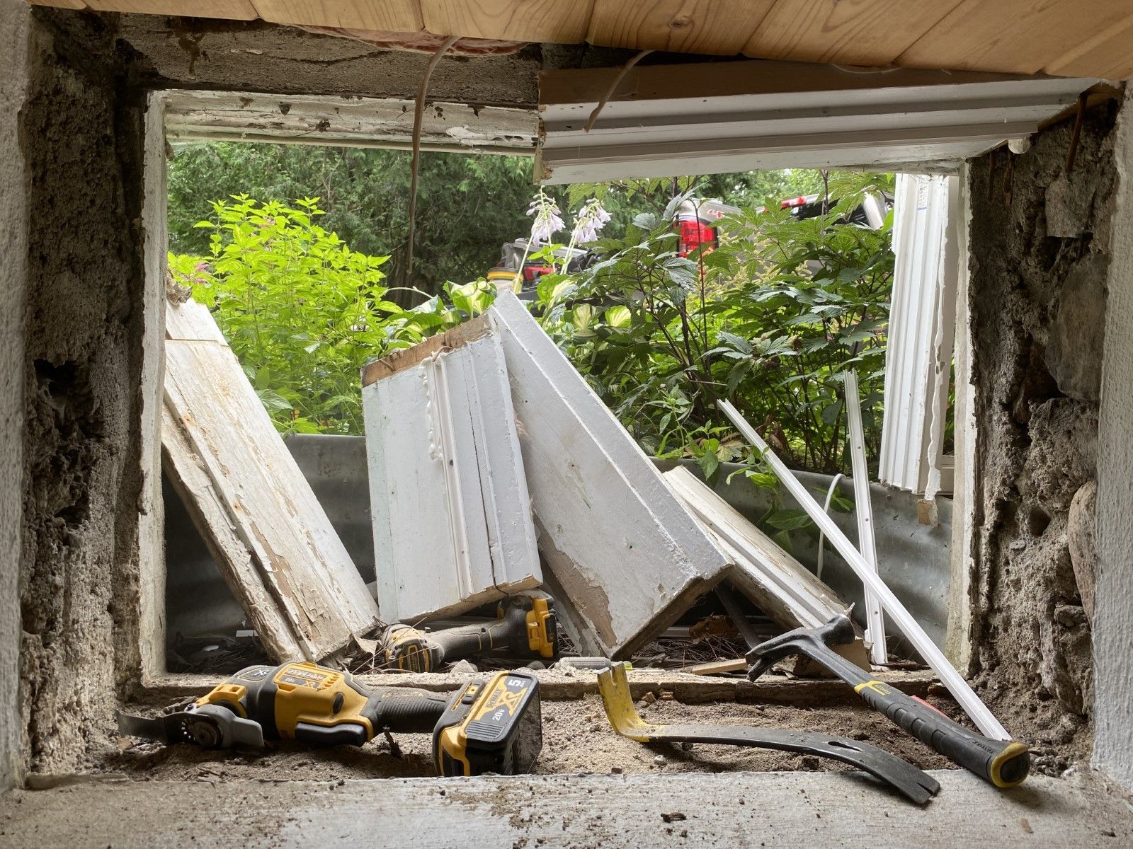 A window in a building under construction with tools on the floor.