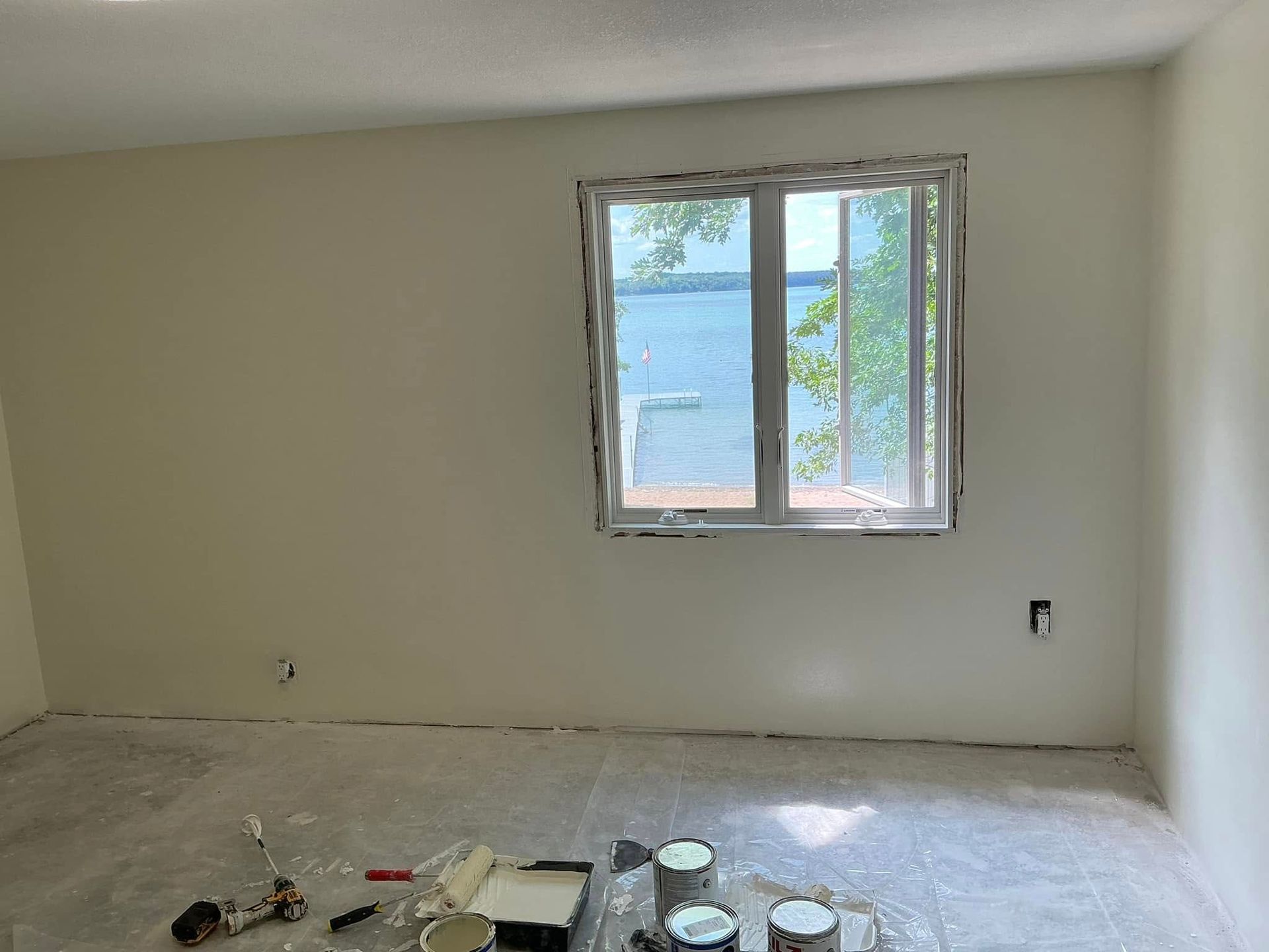 A room with white walls and a window with a view of the water.