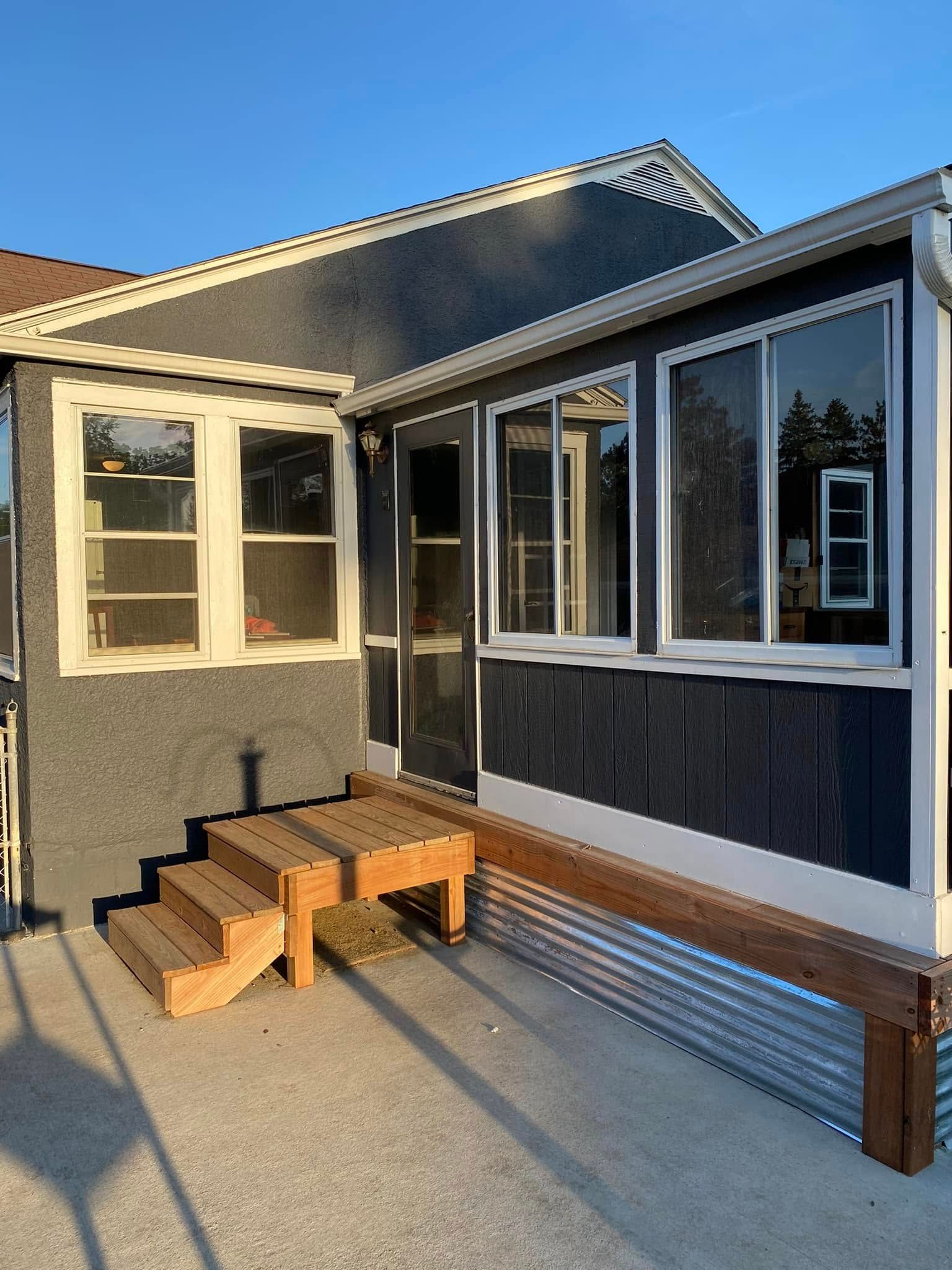 A small house with a screened in porch and stairs.