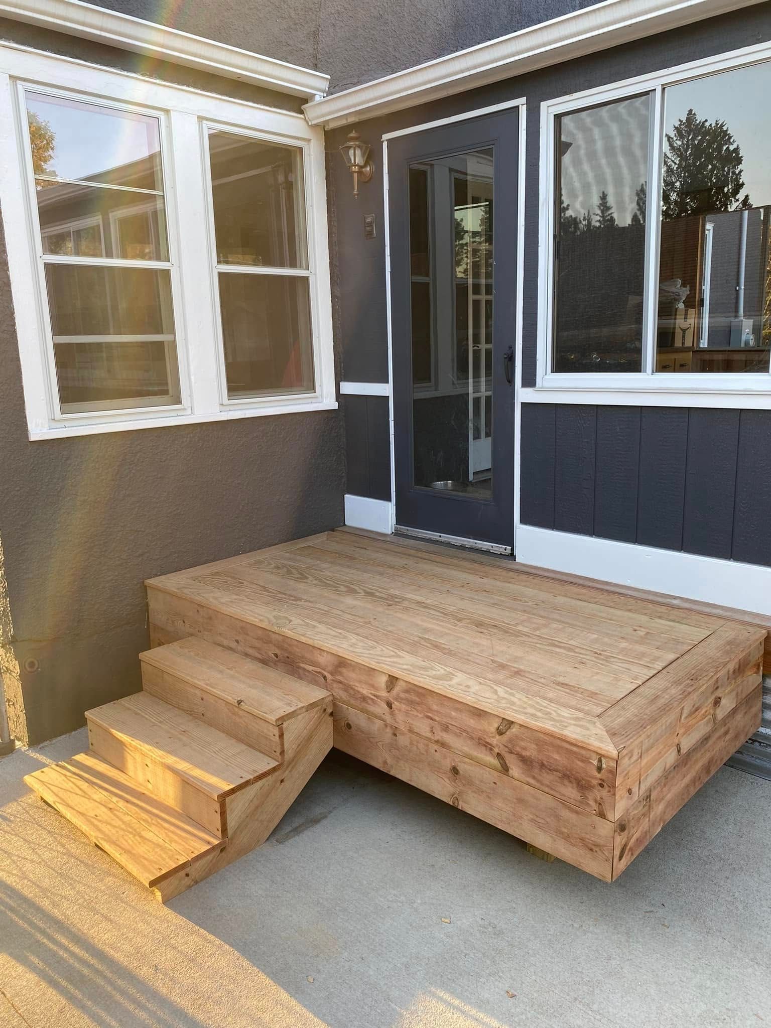 A wooden deck with stairs is in front of a house.