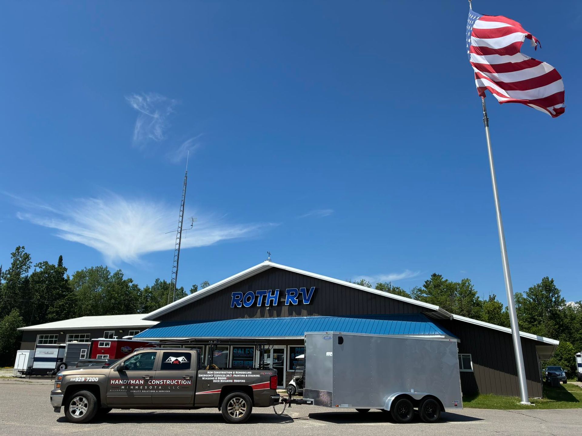 A truck with a trailer attached to it is parked in front of a building.