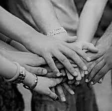 A close-up of several hands stacked together in a circle, symbolizing unity and cooperation.