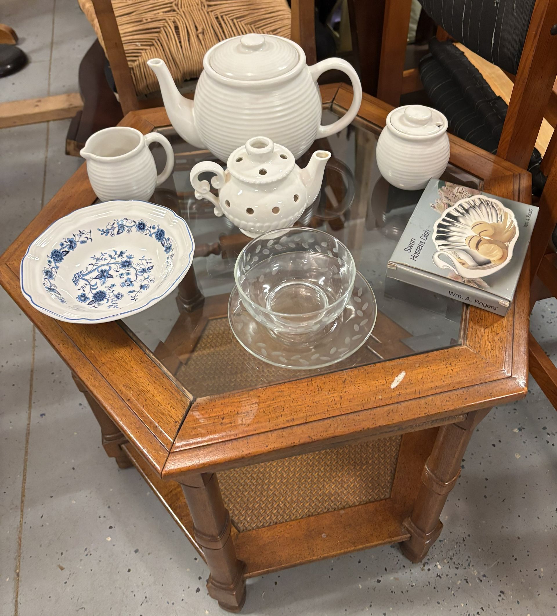 A glass-topped hexagonal wooden table displays several ceramic teaware pieces, a glass teacup, and a decorative box.