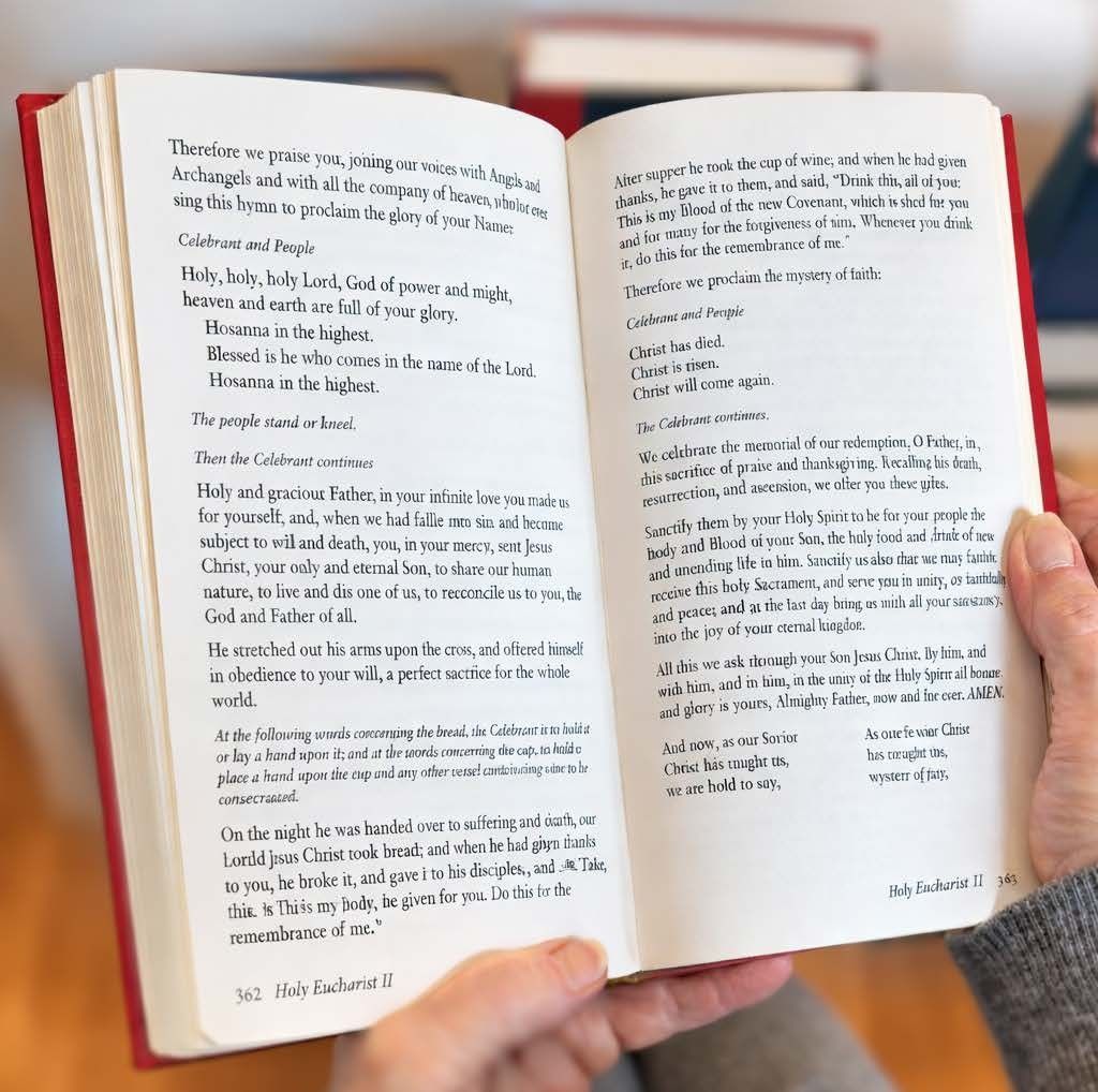 A person holds an open red-bound book displaying two pages of printed text.