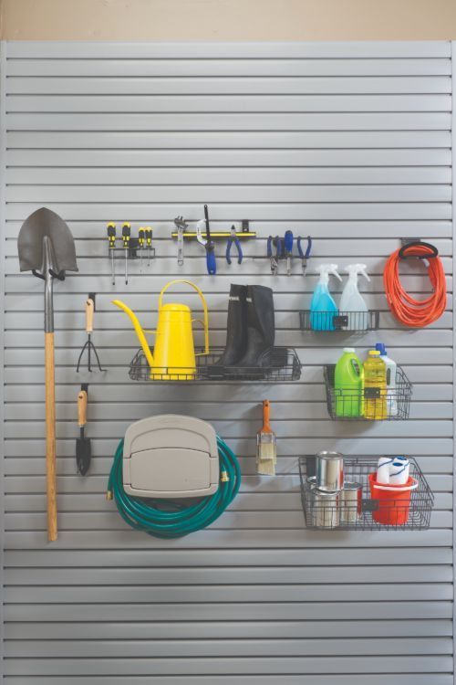 Garage organization system with gardening tools hanging on a horizontal slat wall.