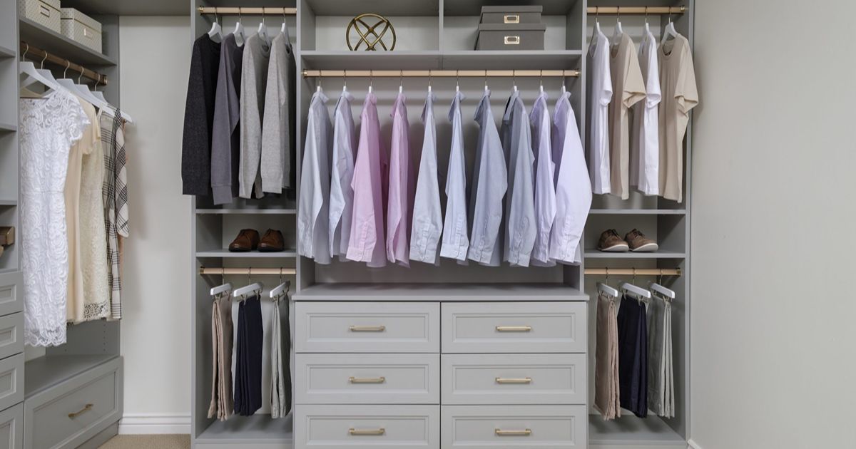 Gray walk-in closet with neatly organized clothing, including shirts, pants, and accessories. Neutral tones and a modern design are featured.