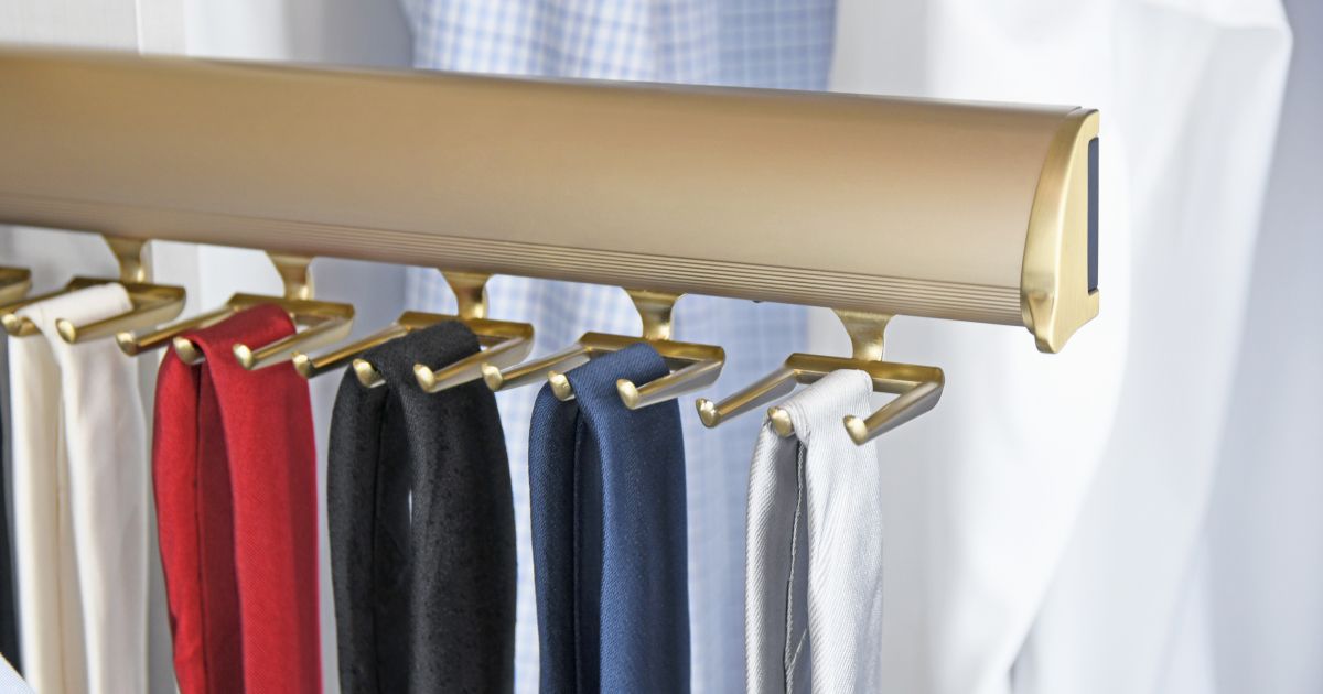 Gold tie rack holding assorted colored ties against a white shirt.
