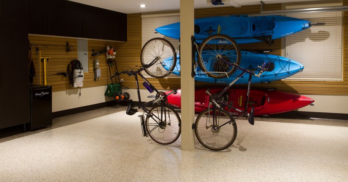 Garage with bikes, kayaks, and storage on wood-paneled walls, with a white speckled floor.