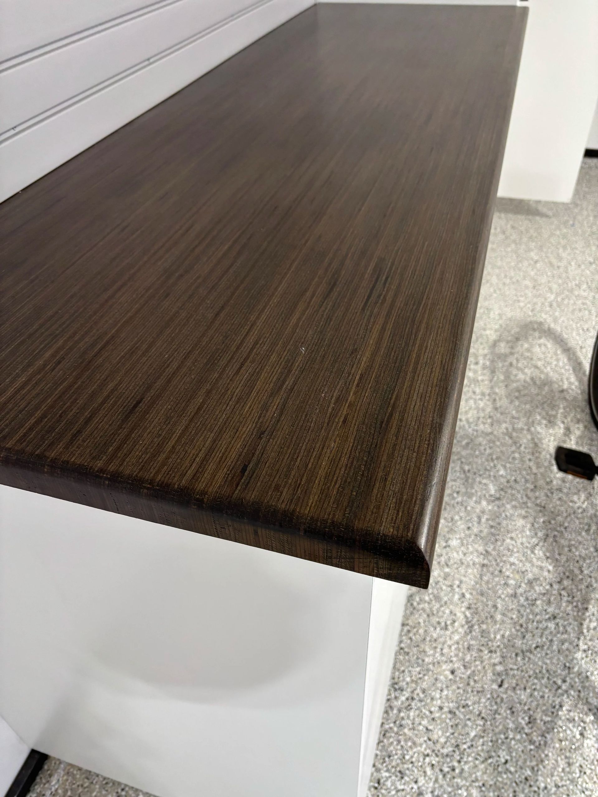 Dark wood countertop on a white cabinet, with a wall of white paneling in the background.
