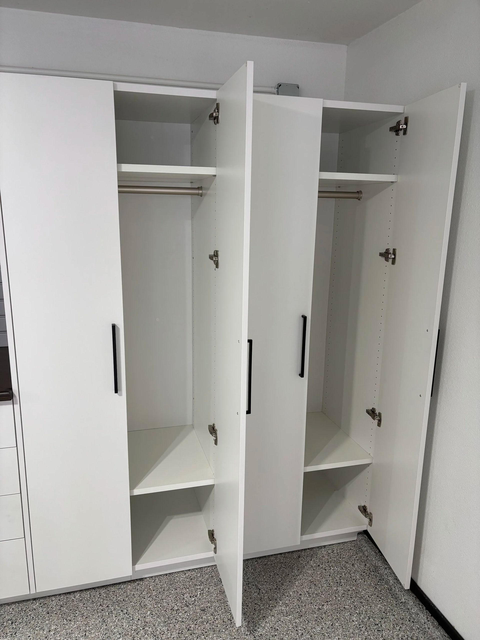 White closet with open doors, shelves, and hanging rods. Interior view.