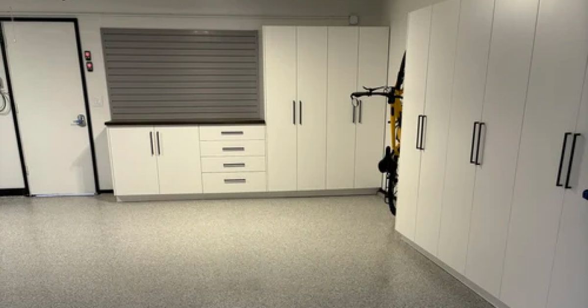 White cabinets and drawers along a garage wall; gray speckled floor.