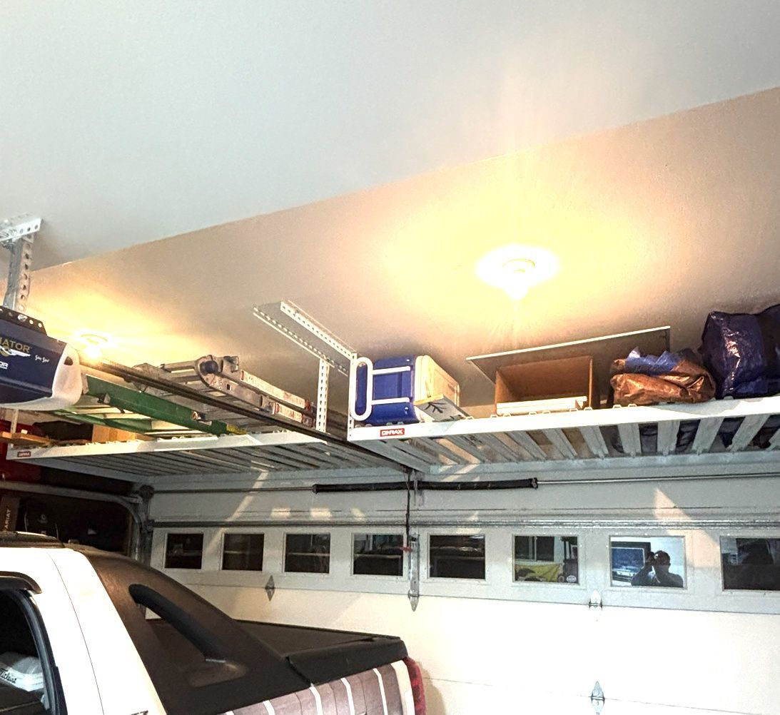 Garage interior with overhead storage shelves; a car is parked below.