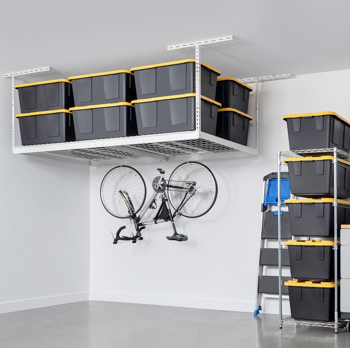 Garage storage: Overhead shelf with bins, bike on wall, and shelving with bins.