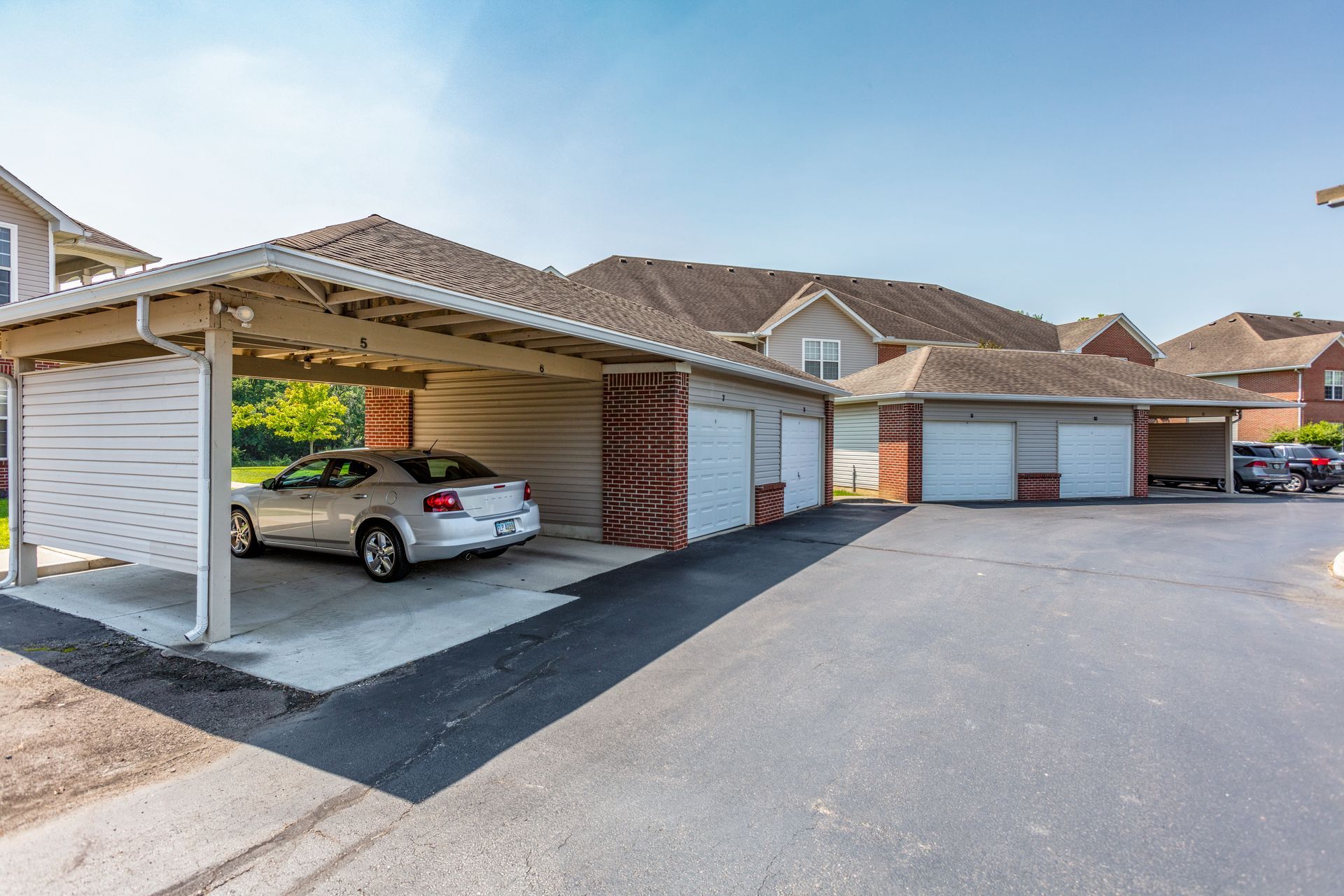 A view of a car in a carport area and parking garages.