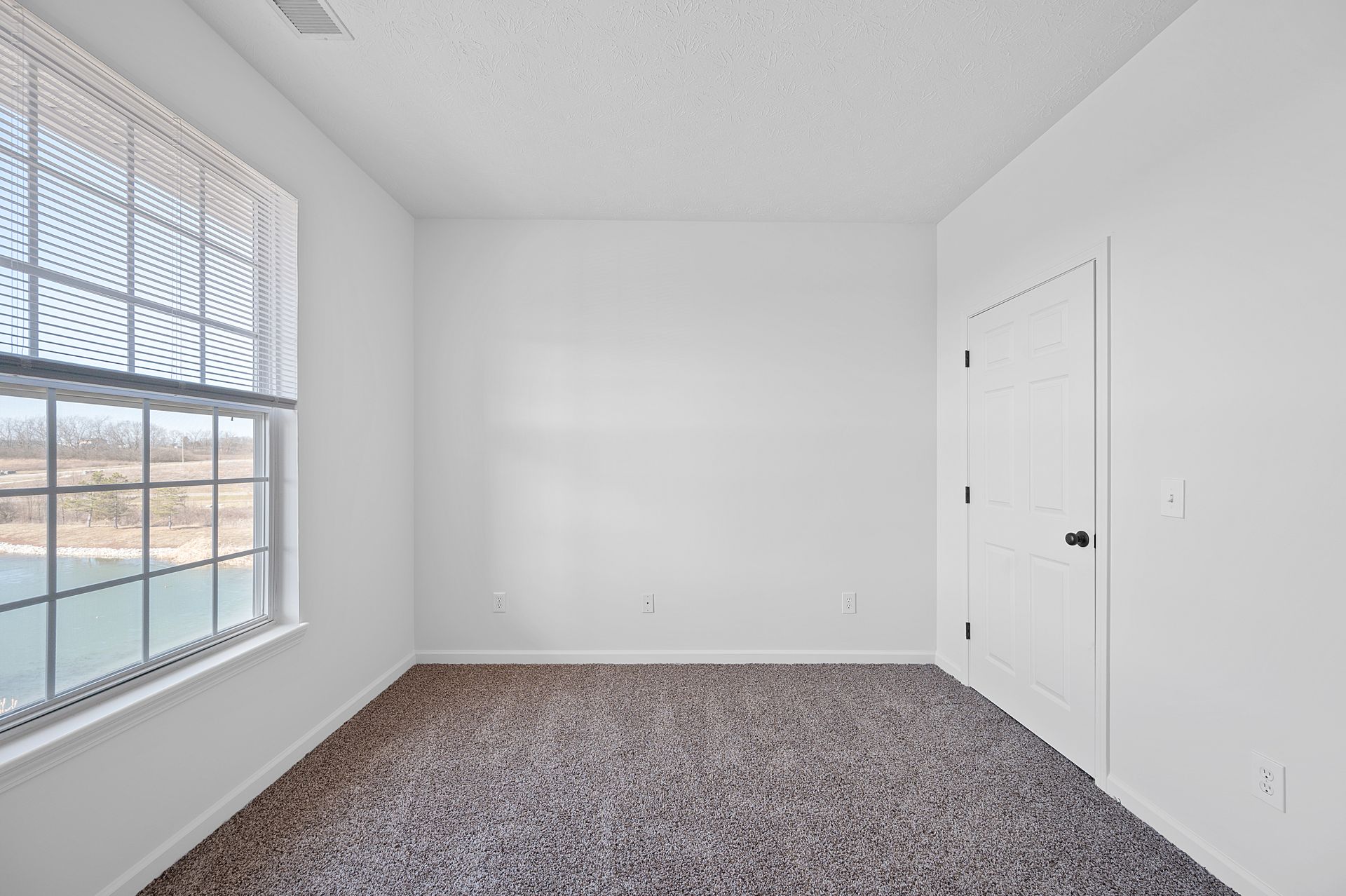 A view of the bedroom, access to the closet and view of the pond through the window.
