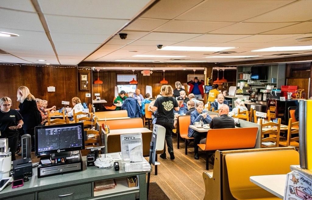 A restaurant filled with people sitting at tables and benches.