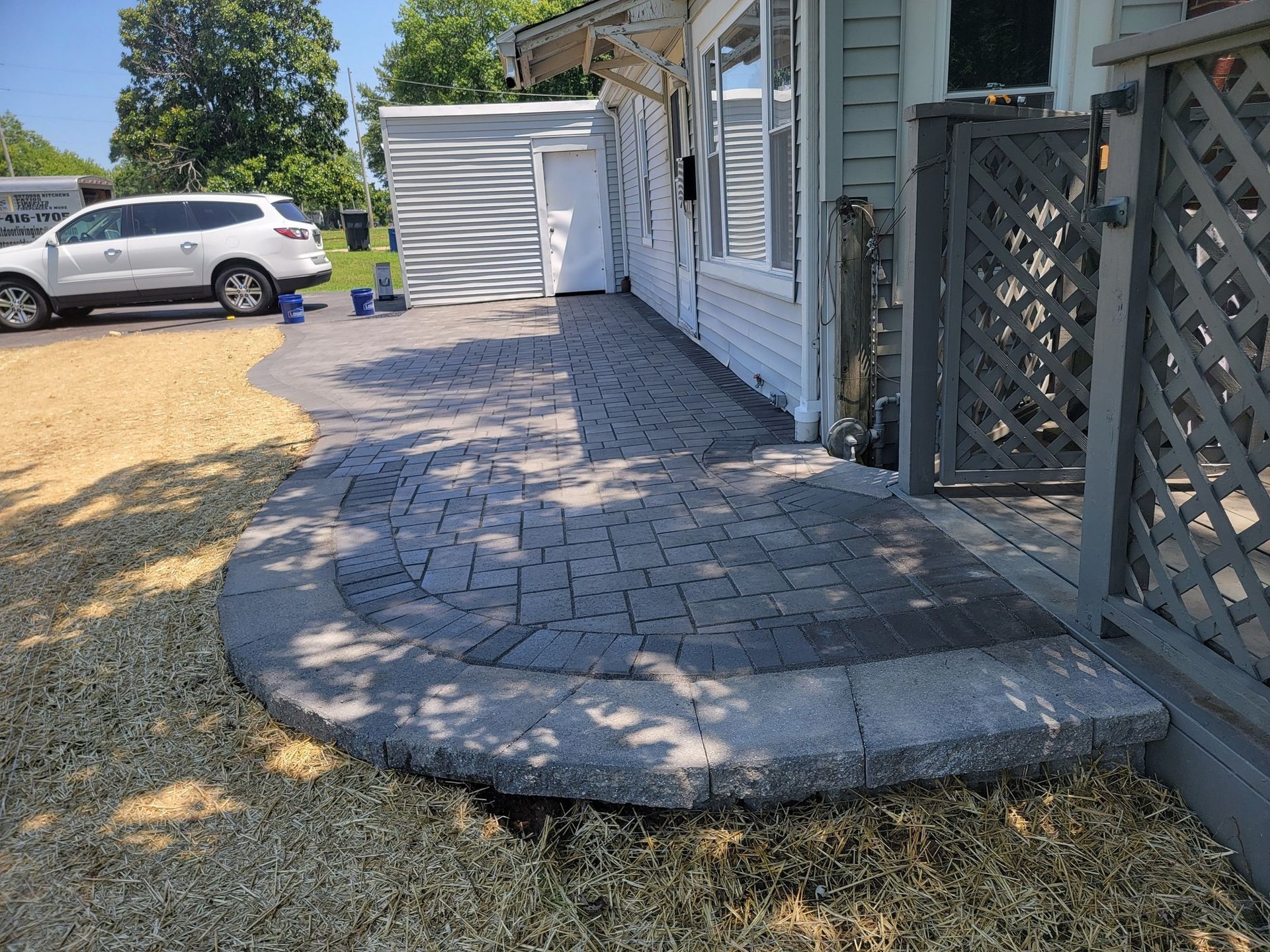 A car is parked in front of a house with a patio in front of it.