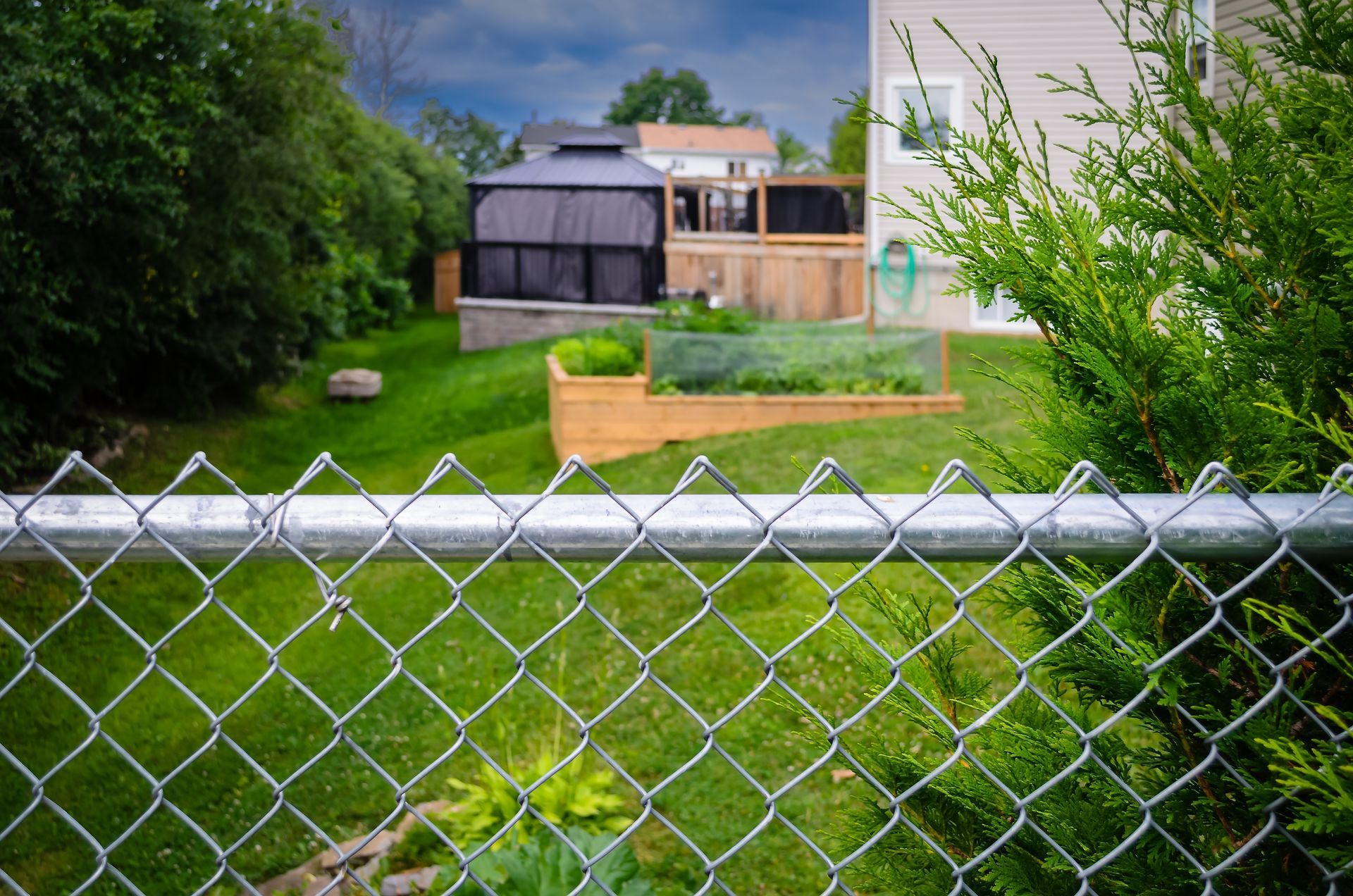 A black metal fence surrounds a gravel path in a yard.