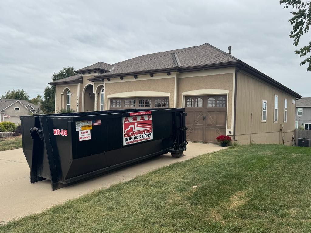 Construction site: pile of wood scraps in front of a partially built house with exposed wood framing.