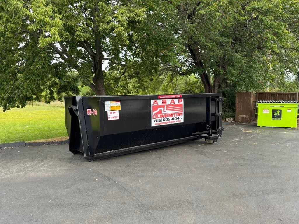 Construction site: pile of wood scraps in front of a partially built house with exposed wood framing.