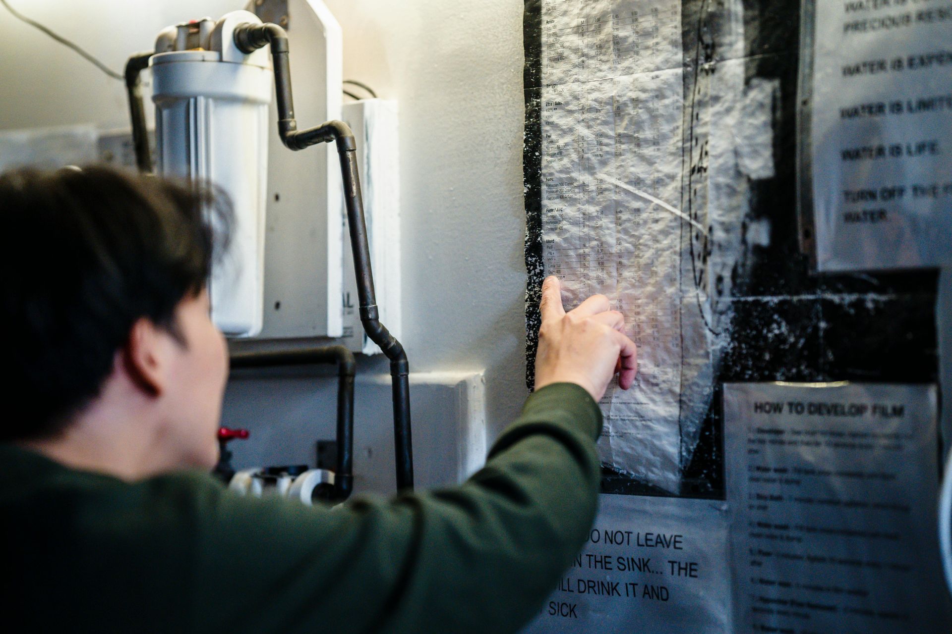 A man is pointing at a piece of paper on a wall.