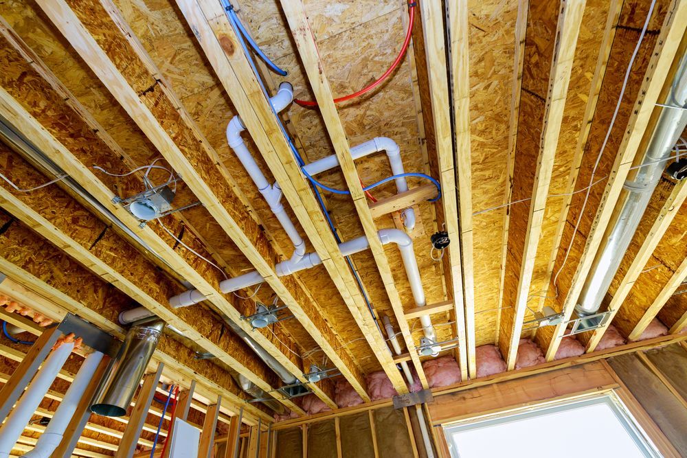 The ceiling of a house under construction with pipes coming out of it.