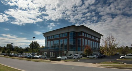 A large building with a lot of windows and cars parked in front of it.