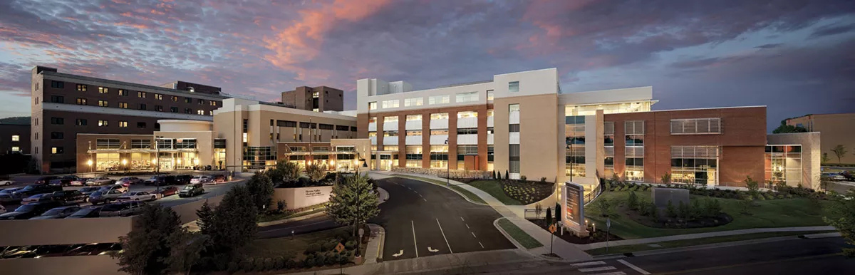 A large building with a lot of windows and cars parked in front of it.