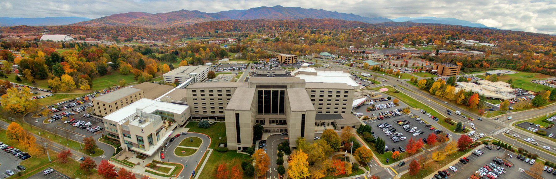 An aerial view of a large building surrounded by trees and parking lots.