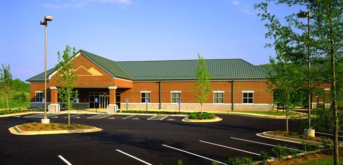 A brick building with a green roof and a parking lot in front of it