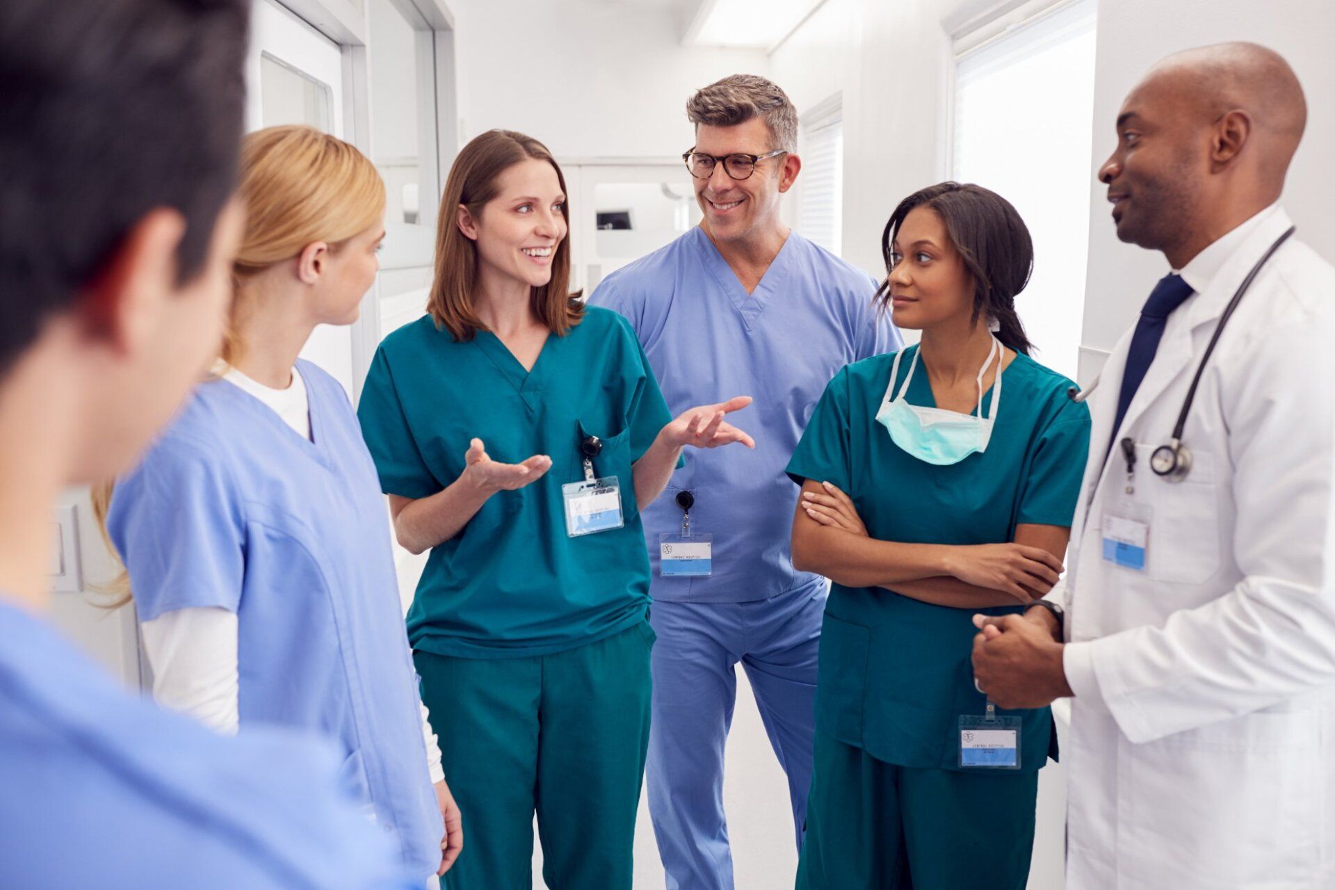 A group of doctors and nurses are standing in a hospital hallway talking to each other.