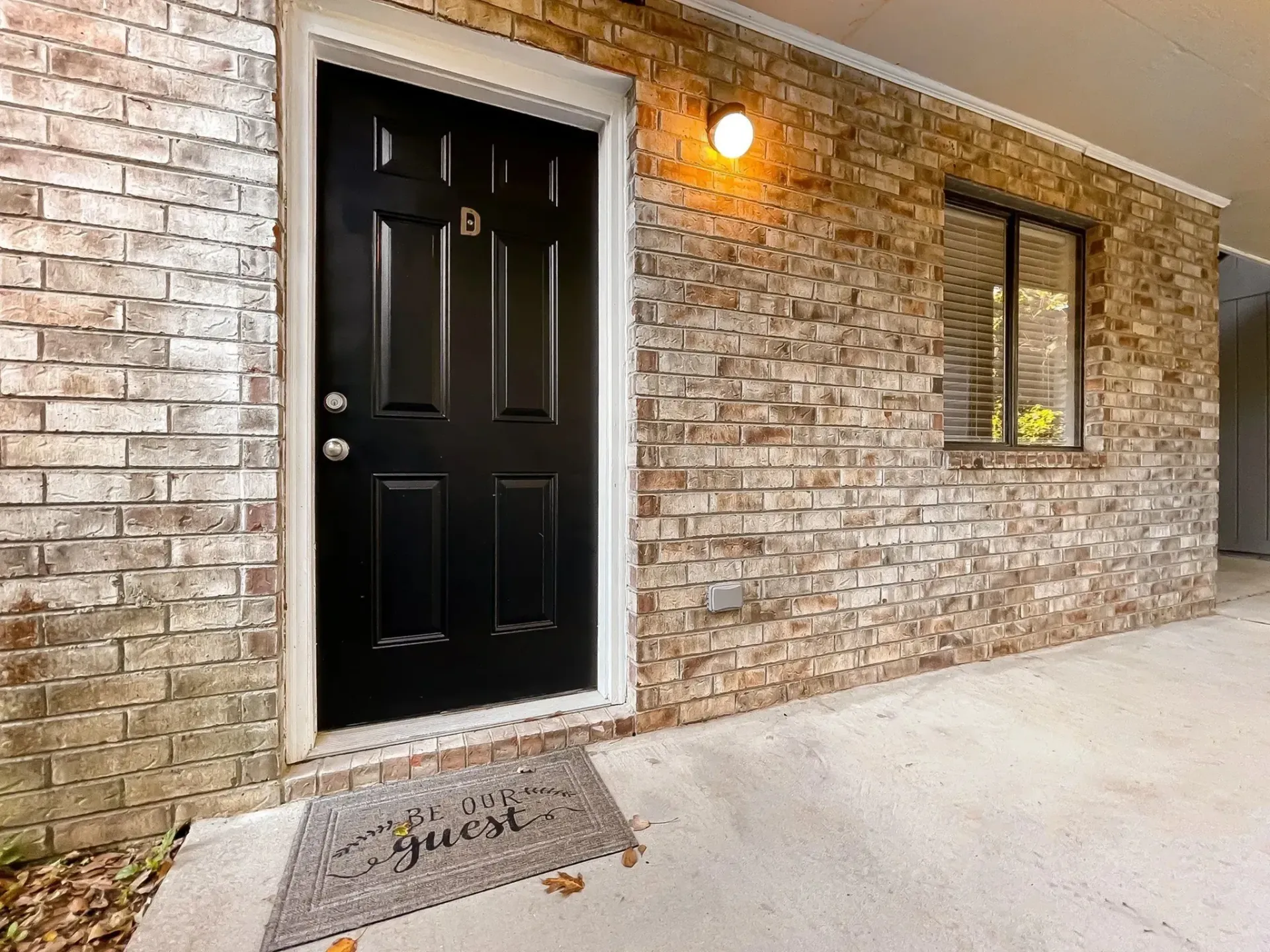 Entrance to an apartment unit featuring a black door and a welcome mat.
