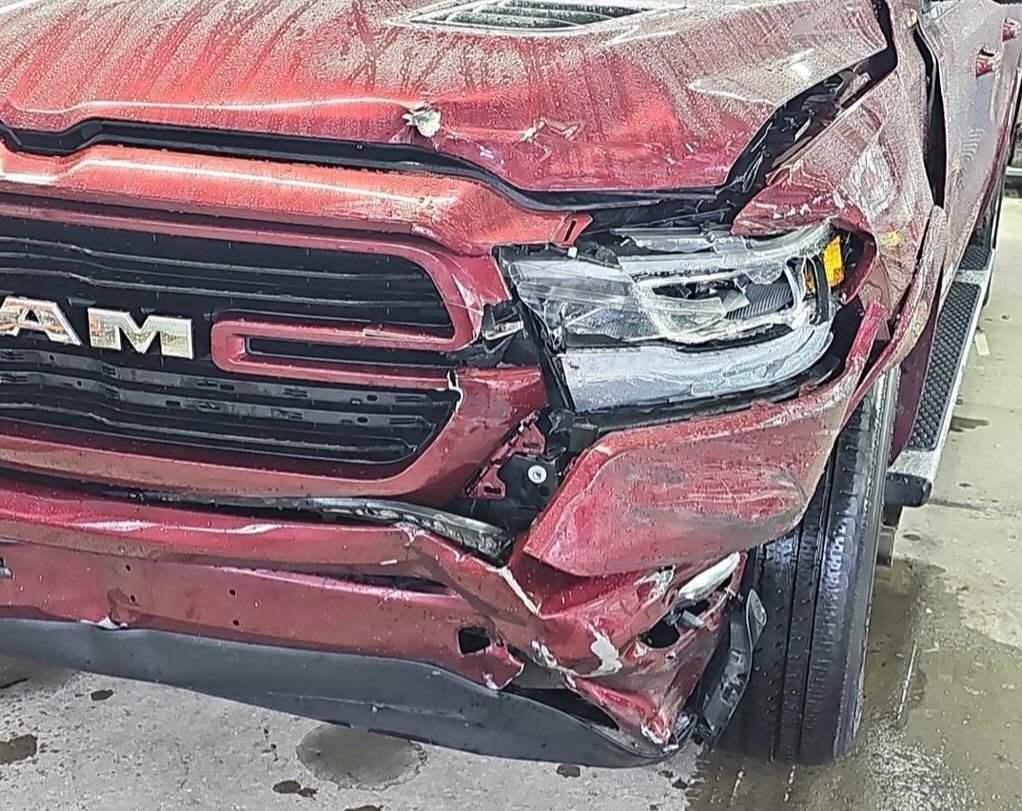 Damaged red Ram truck front end, headlights broken, front panel crumpled.