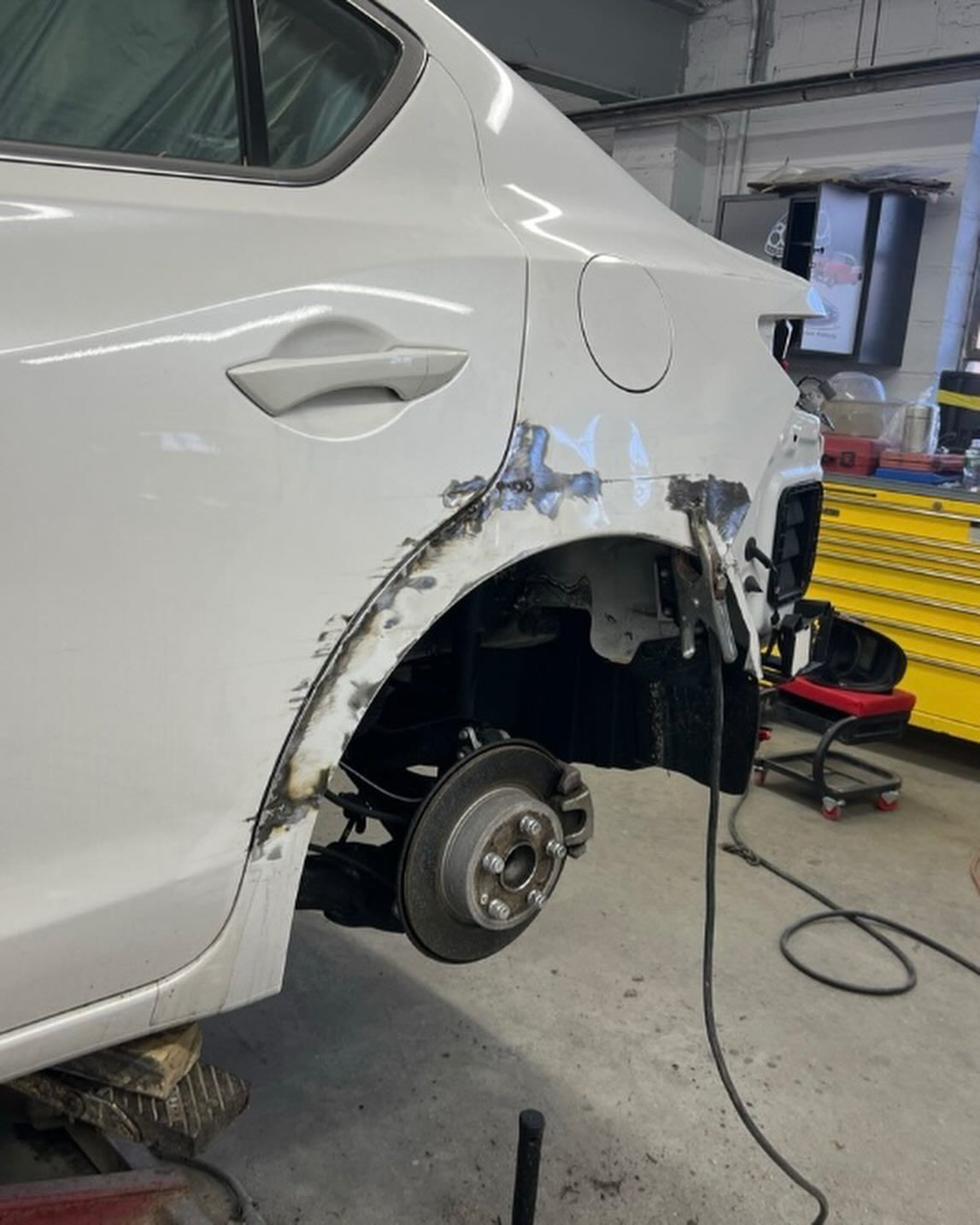 A person in black gloves polishes a red car with a buffing machine, close-up shot.