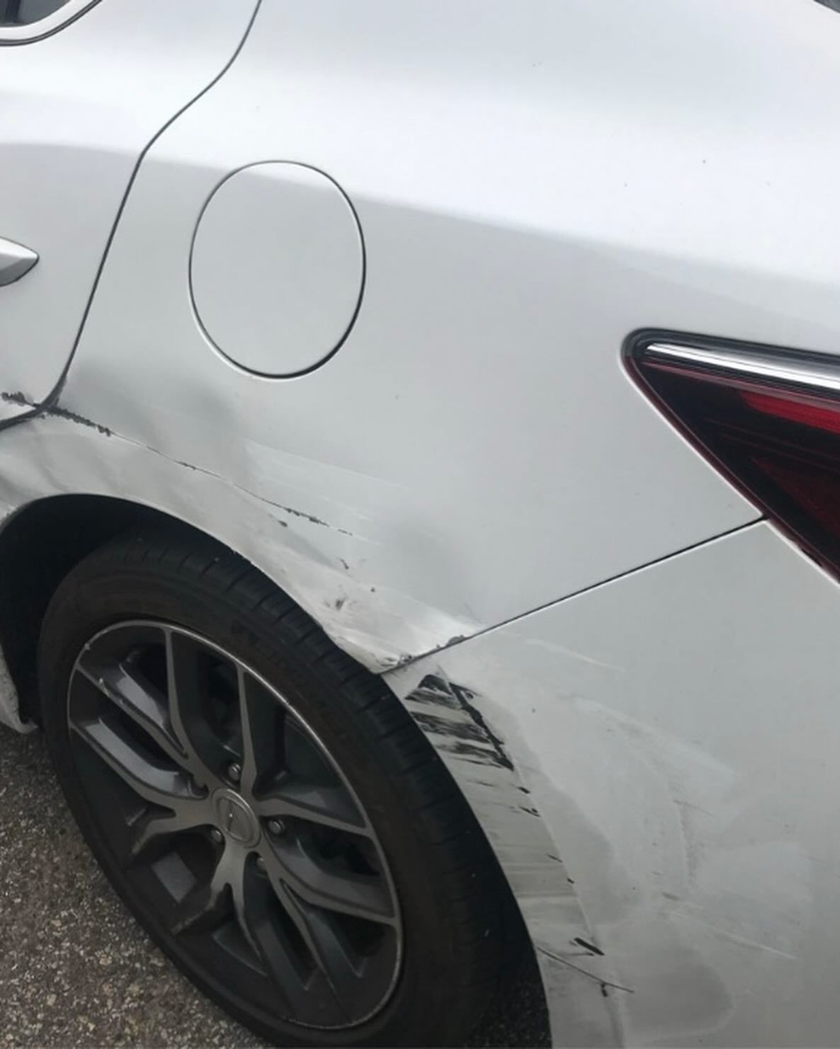 Person polishing black car with an electric buffer in a garage.