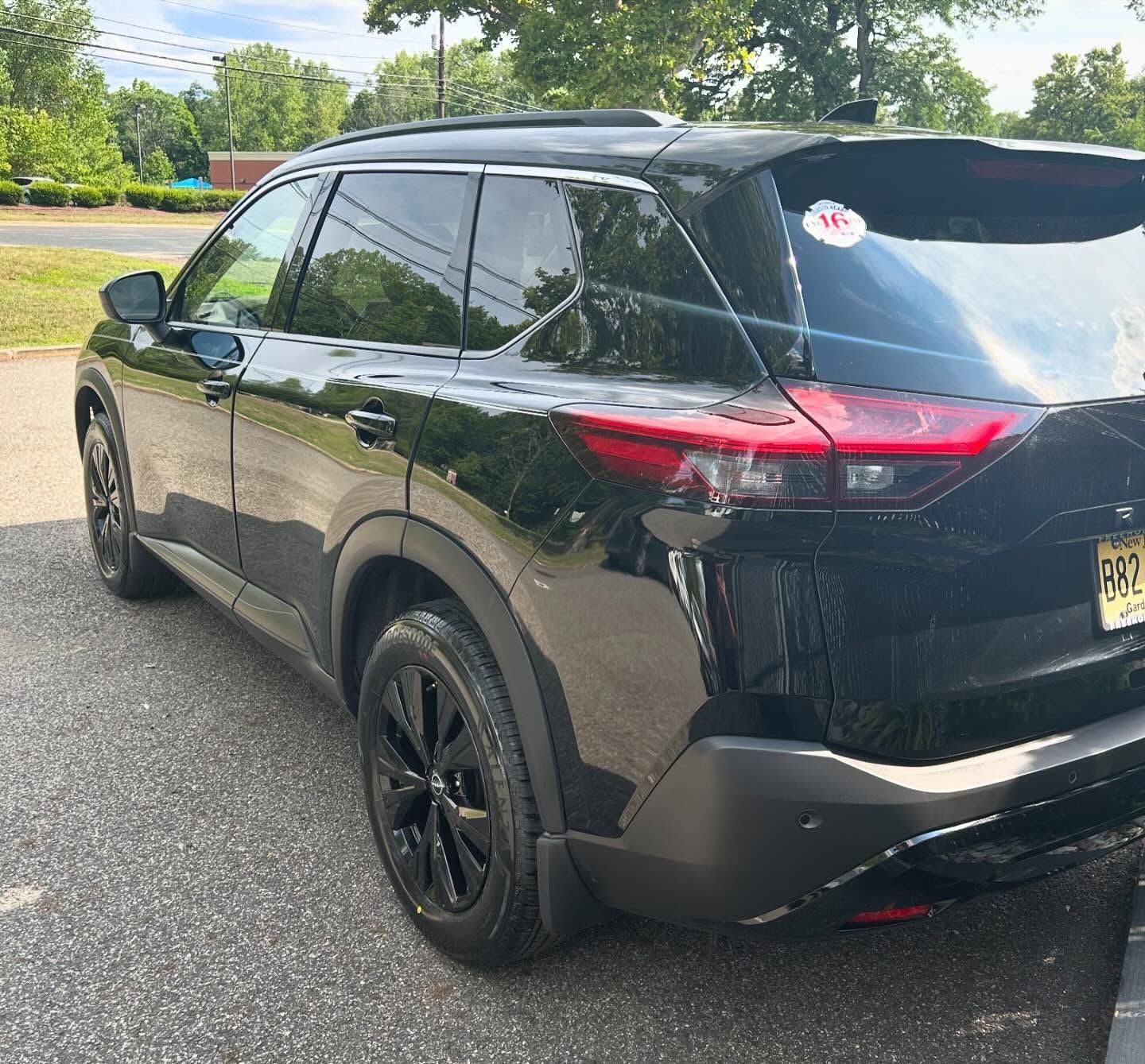 Black Nissan SUV parked on asphalt. Black wheels, tinted windows. Daytime, outdoors.