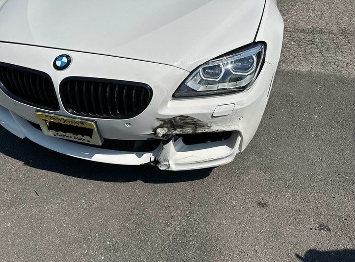 Person spray-painting a red car with a spray gun in a body shop.