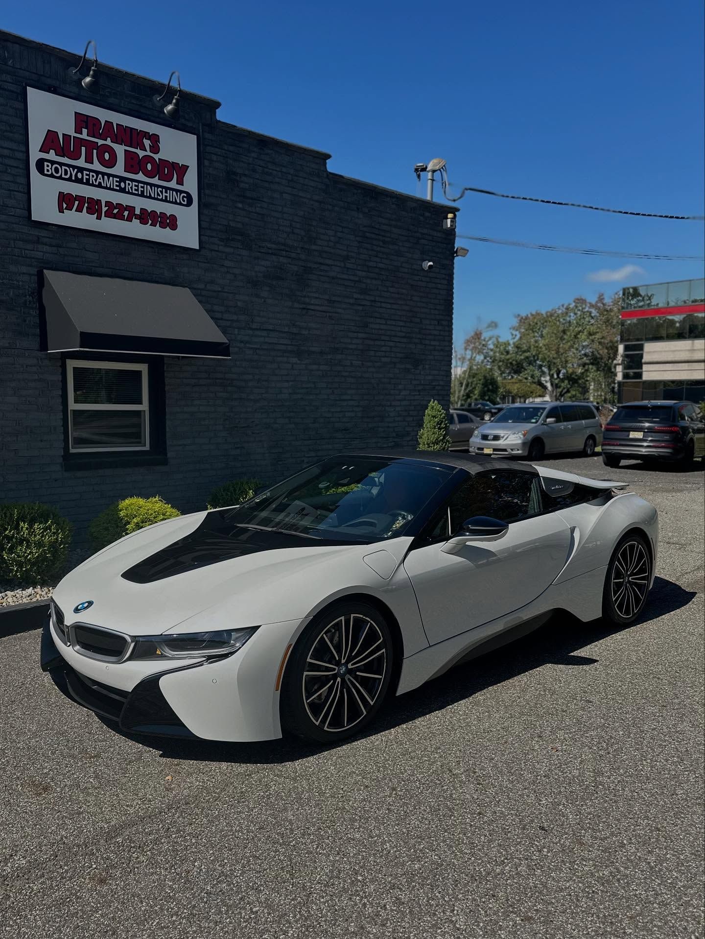 Person sanding a car bumper with a sanding block and wiping it with a blue cloth in a repair shop.