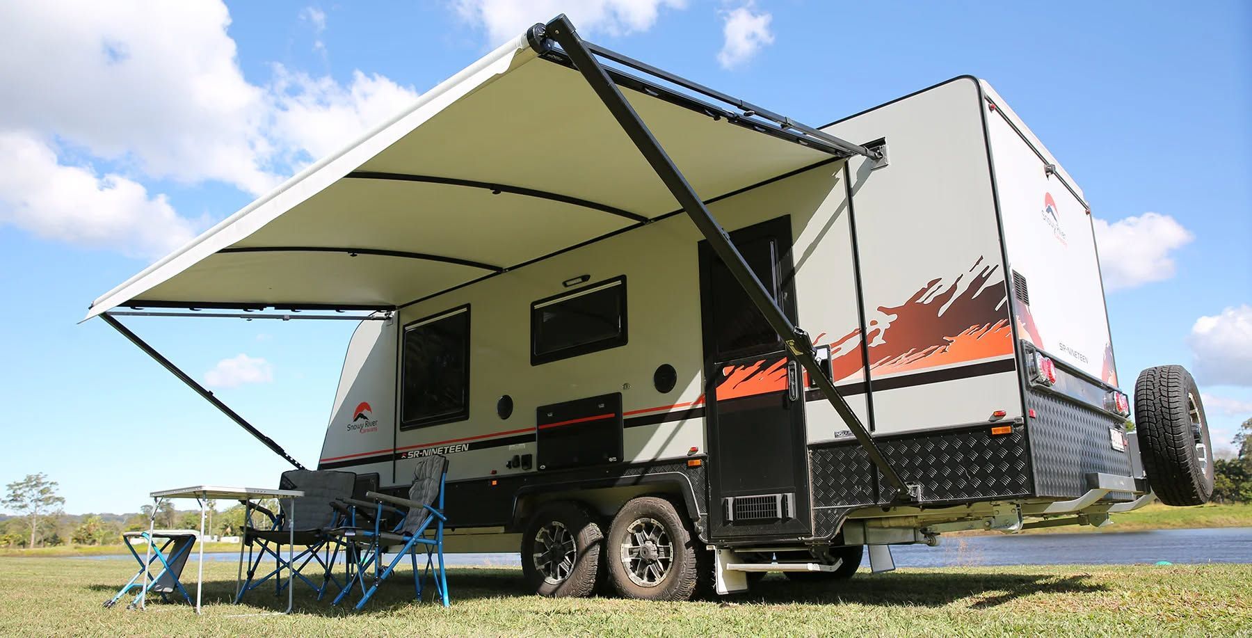 Tan and Black Caravan With Awning Extended on Grass Field — Caravan and Trailer Clinic Geelong in Breakwater, VIC