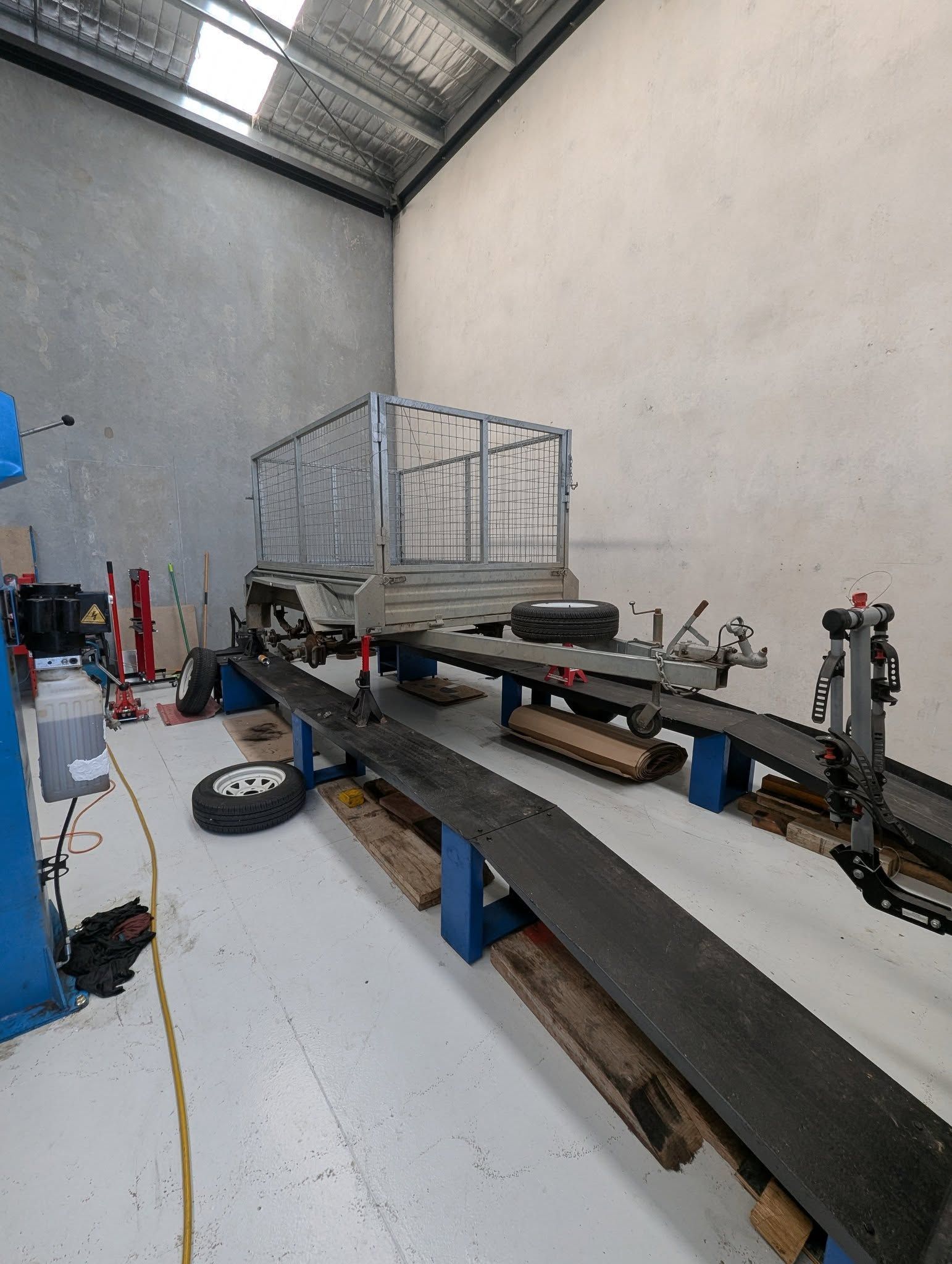 Trailer on a Lift in a Workshop, Grey Metal Cage — Caravan and Trailer Clinic Geelong in Breakwater, VIC
