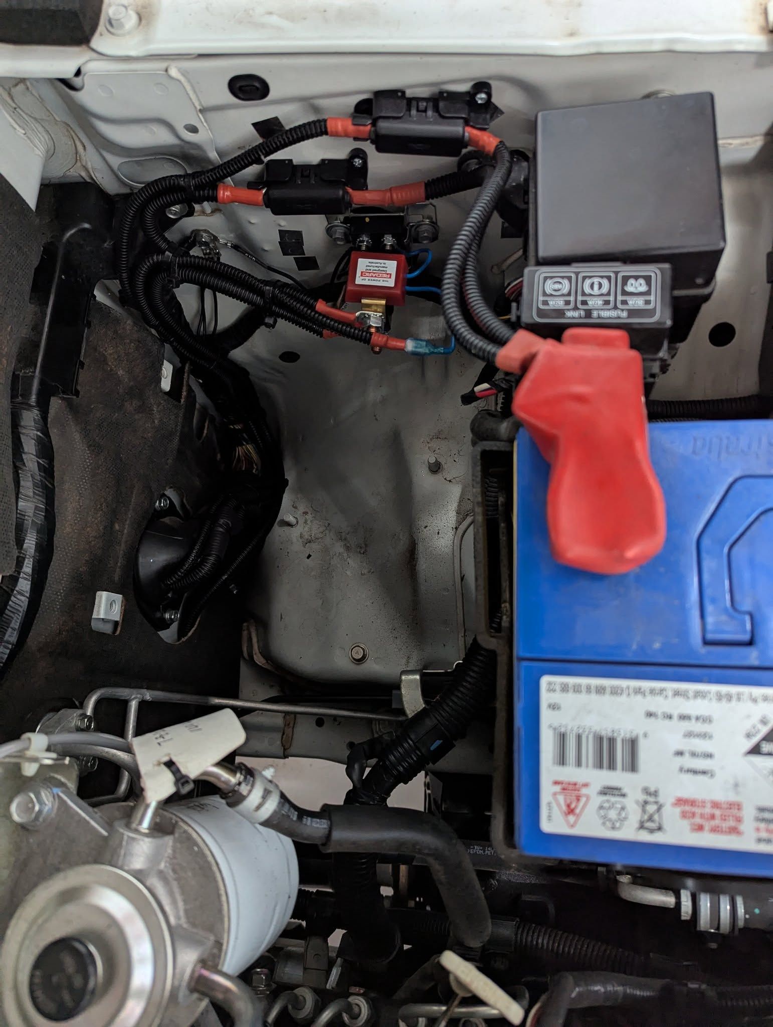 Car battery bay with battery, fuses, and wiring. Black wires and red battery terminal cover. — Caravan and Trailer Clinic Geelong in Breakwater, VIC