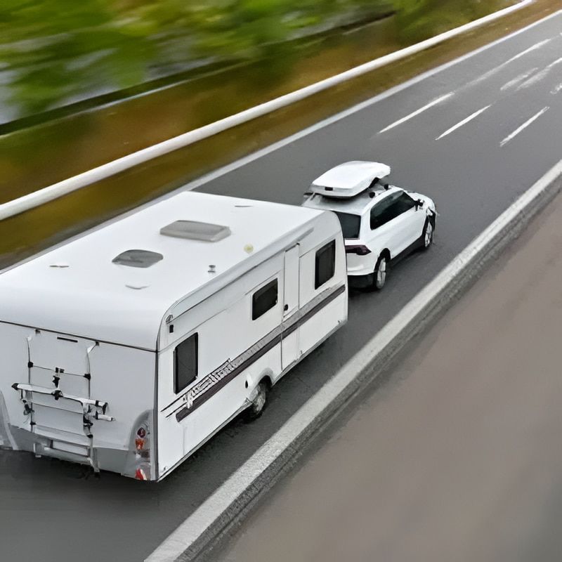 White SUV towing a white camper on a highway. - Caravan and Trailer Clinic Geelong in Breakwater, VIC