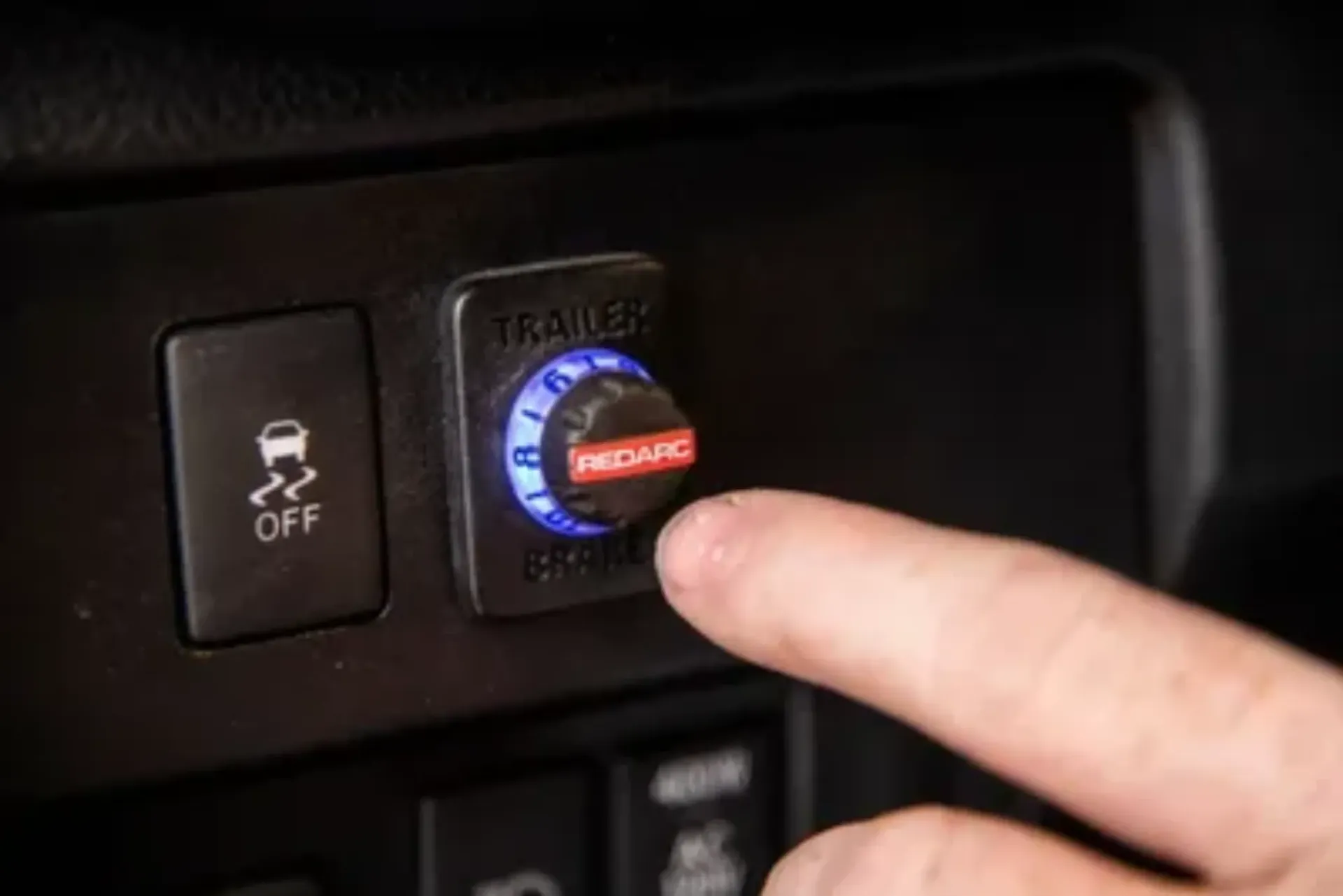 A hand presses a red Recaro trailer brake controller dial in a car, with a button labeled “Off” to the left. — Caravan and Trailer Clinic Geelong in Breakwater, VIC