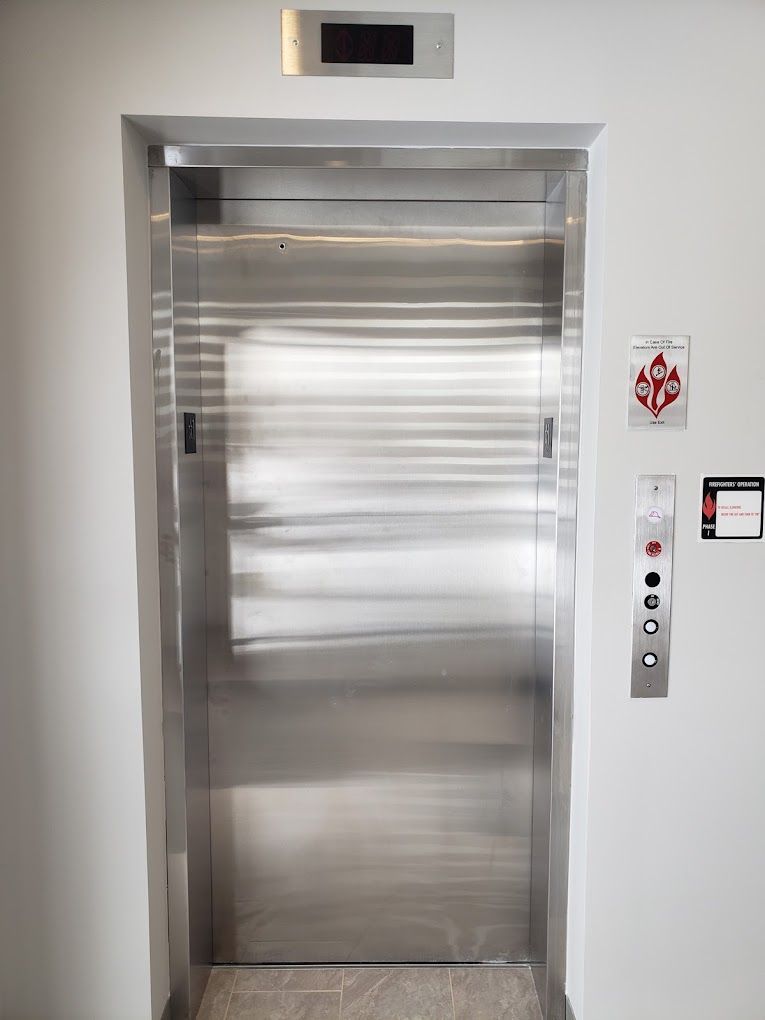 A hallway with elevators and a television on the wall.