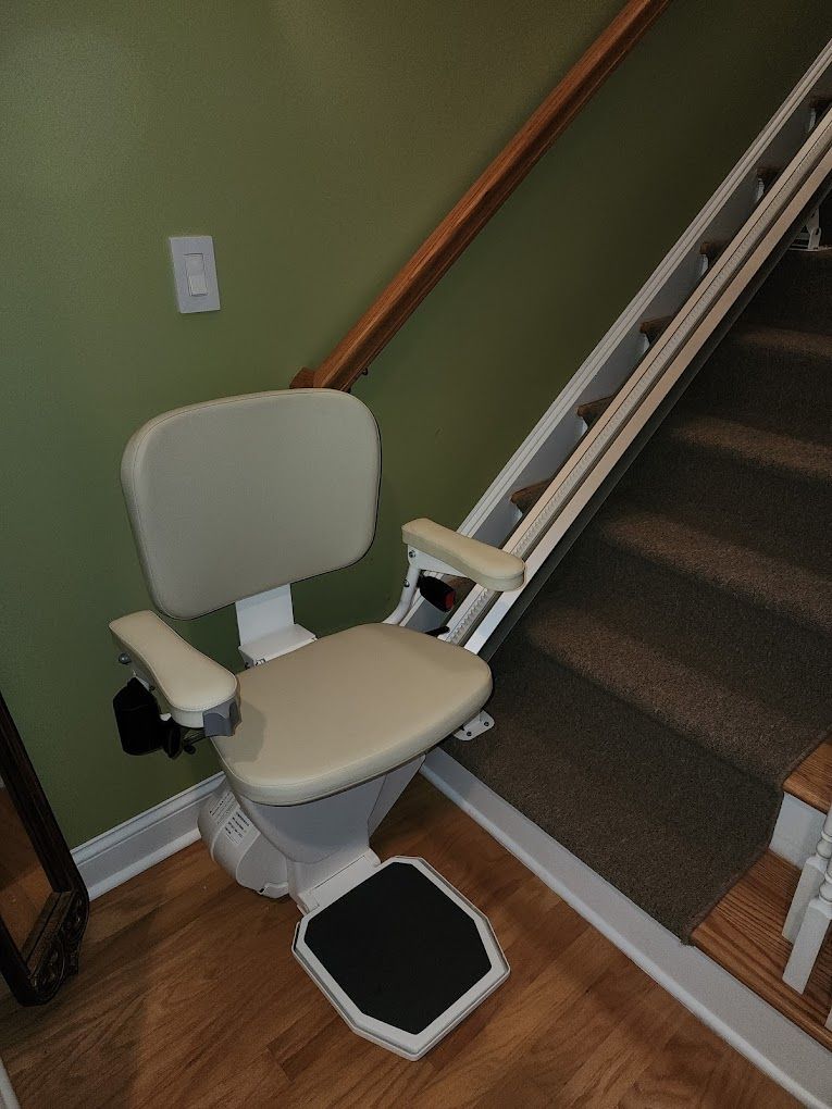 A stair lift is sitting in the corner of a room next to a staircase.