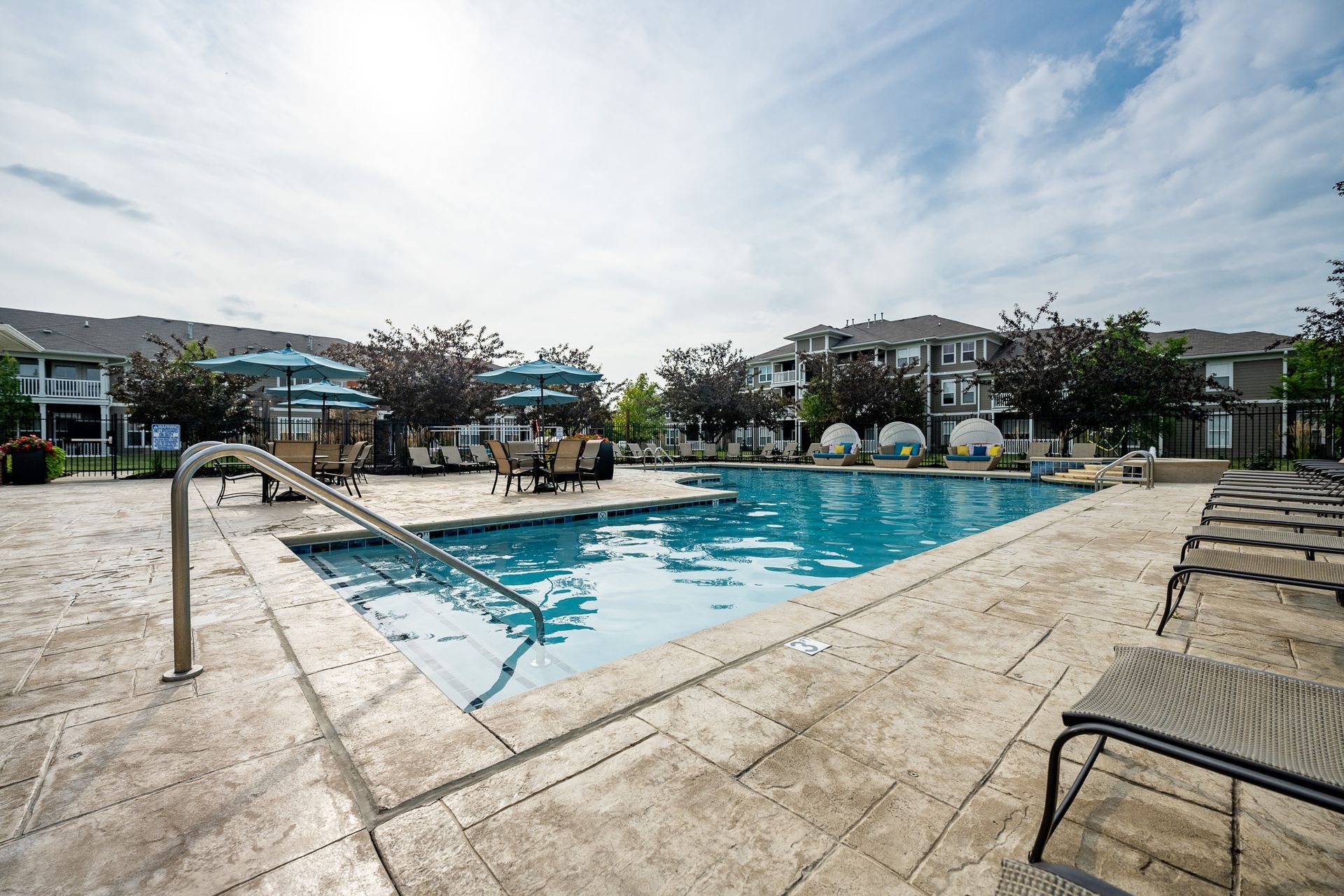 A large swimming pool surrounded by chairs and umbrellas in a residential area at Maple Knoll Apartments