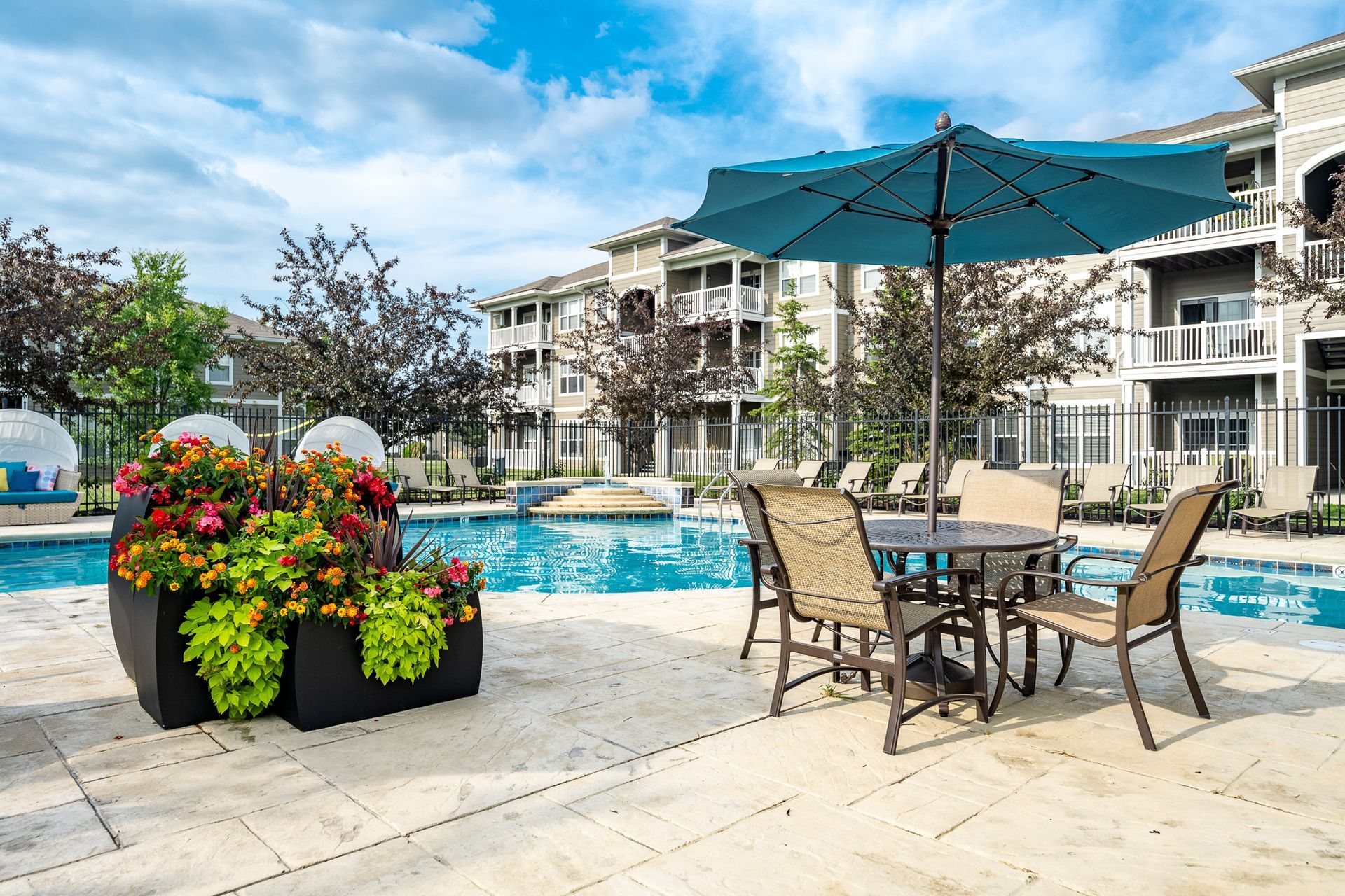 A swimming pool with a table and chairs under an umbrella at Maple Knoll Apartments