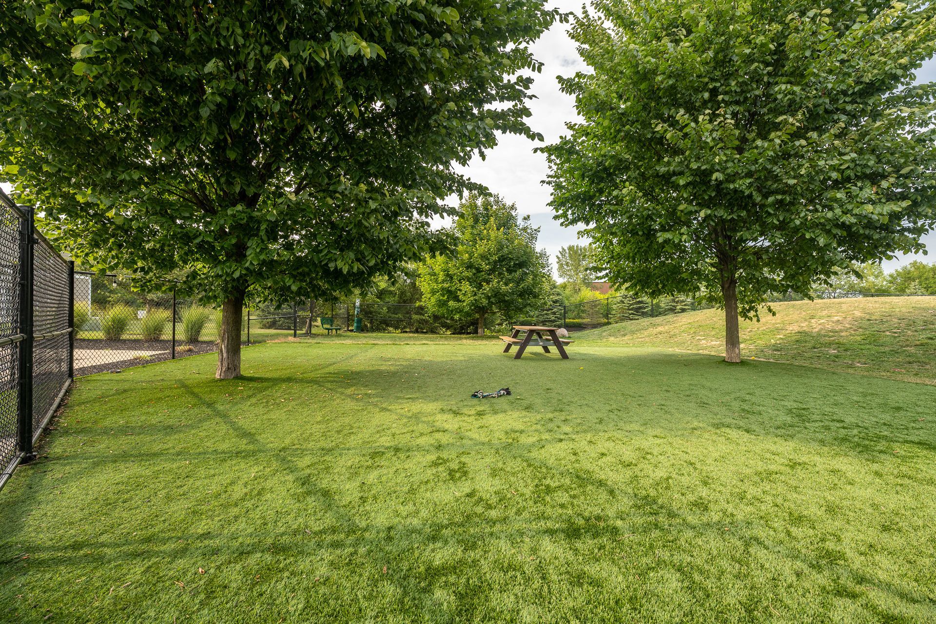 There is a picnic table in the middle of the grass in the park at Maple Knoll Apartments